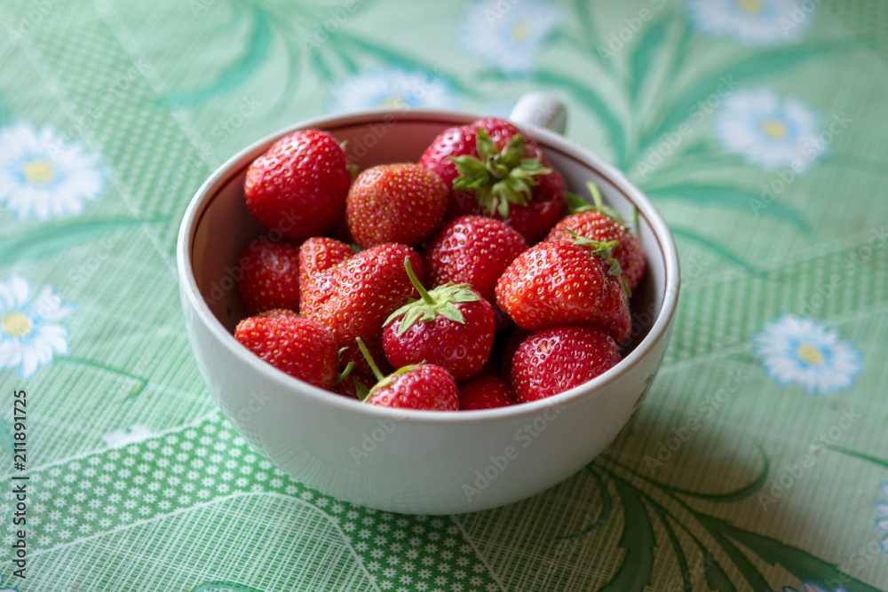 ripe strawberry berry with green leafs in a plate on a green background ripe strawberry berry with green leafs in a plate on a green background
