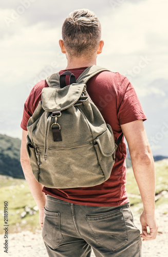 Junger Mann mit Wanderrucksack blickt in die Ferne