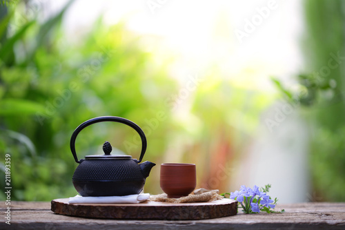 Old black tea pot with brown cup and flower