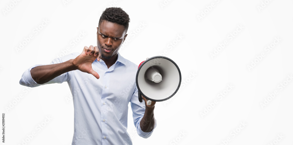 Young african american man holding megaphone with angry face, negative sign showing dislike with thumbs down, rejection concept Young african american man holding megaphone with angry face, negative sign showing dislike with thumbs down, rejection concept