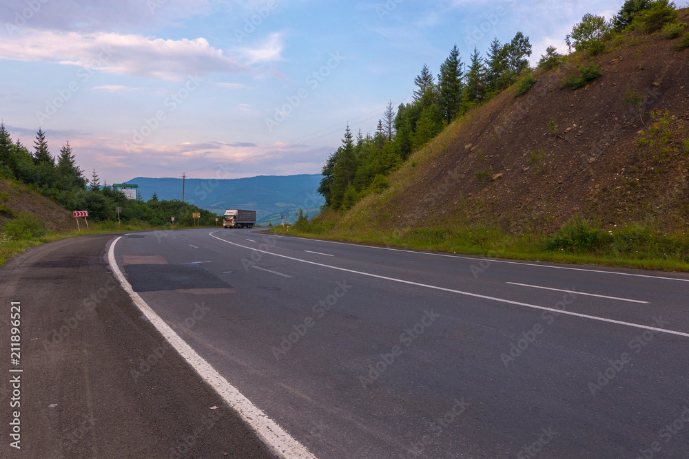 Fototapeta premium The route between the earthen hills along which a large long distance truck is traveling