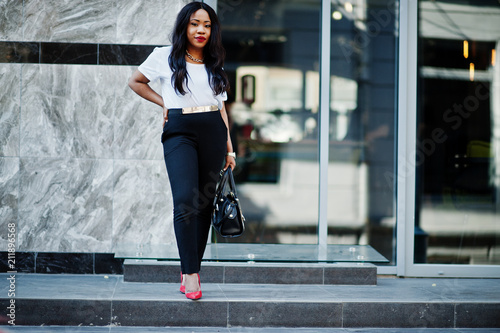 Stylish african american business woman with handbag on streets of city.