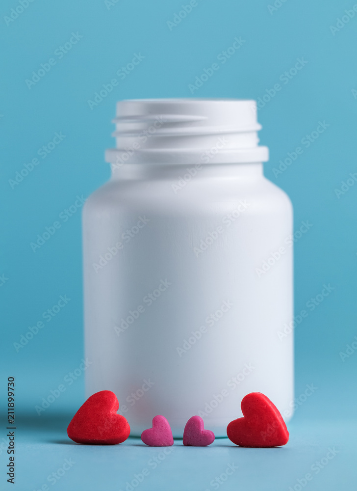 Tablets in the form of heart and a jar for tablets on a blue background Tablets in the form of heart and a jar for tablets on a blue background