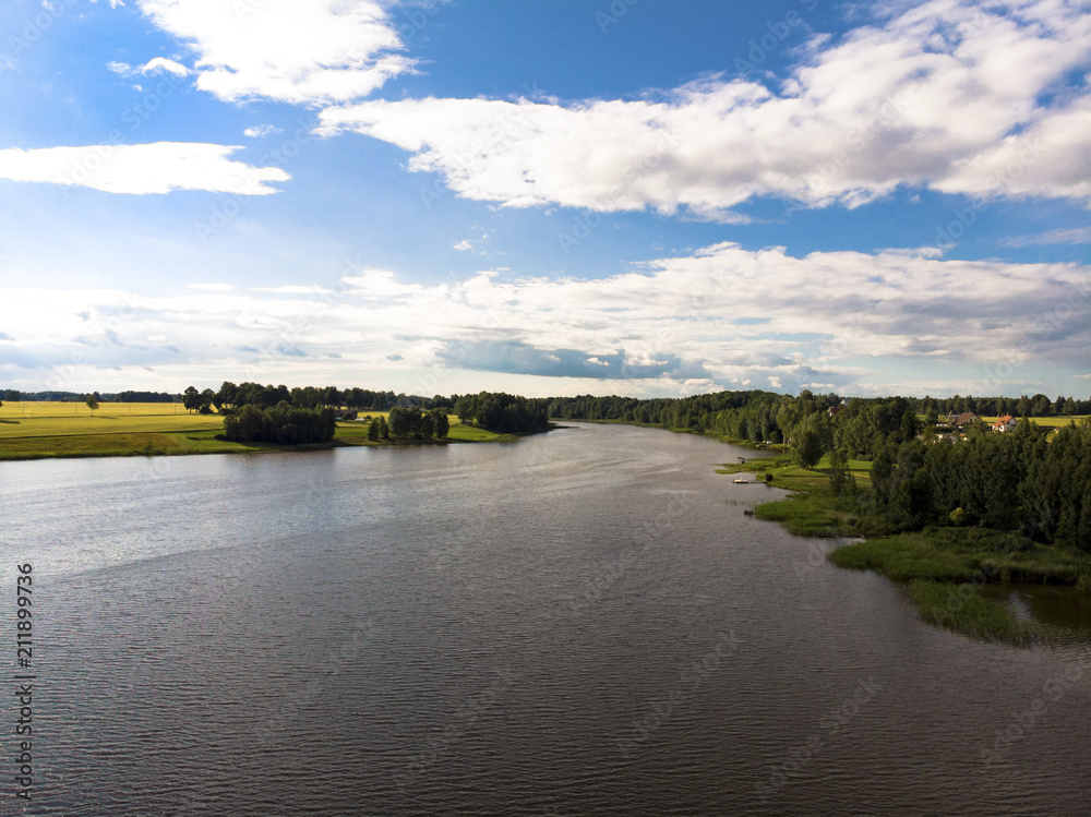 Fototapeta premium Beautiful lake with trees on the sides and bright blue cloudy sky. Beautiful nature landscape
