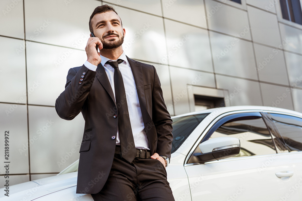handsome businessman talking by smartphone and standing near auto on street handsome businessman talking by smartphone and standing near auto on street