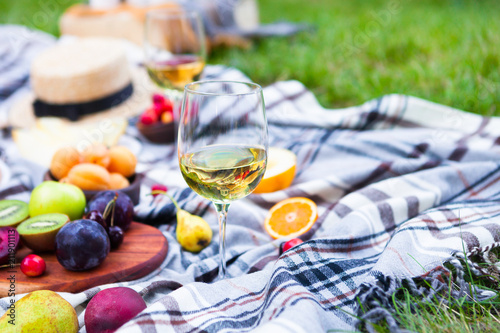 Picnic background with white wine and summer fruits on green grass, summertime party © yatcenko
