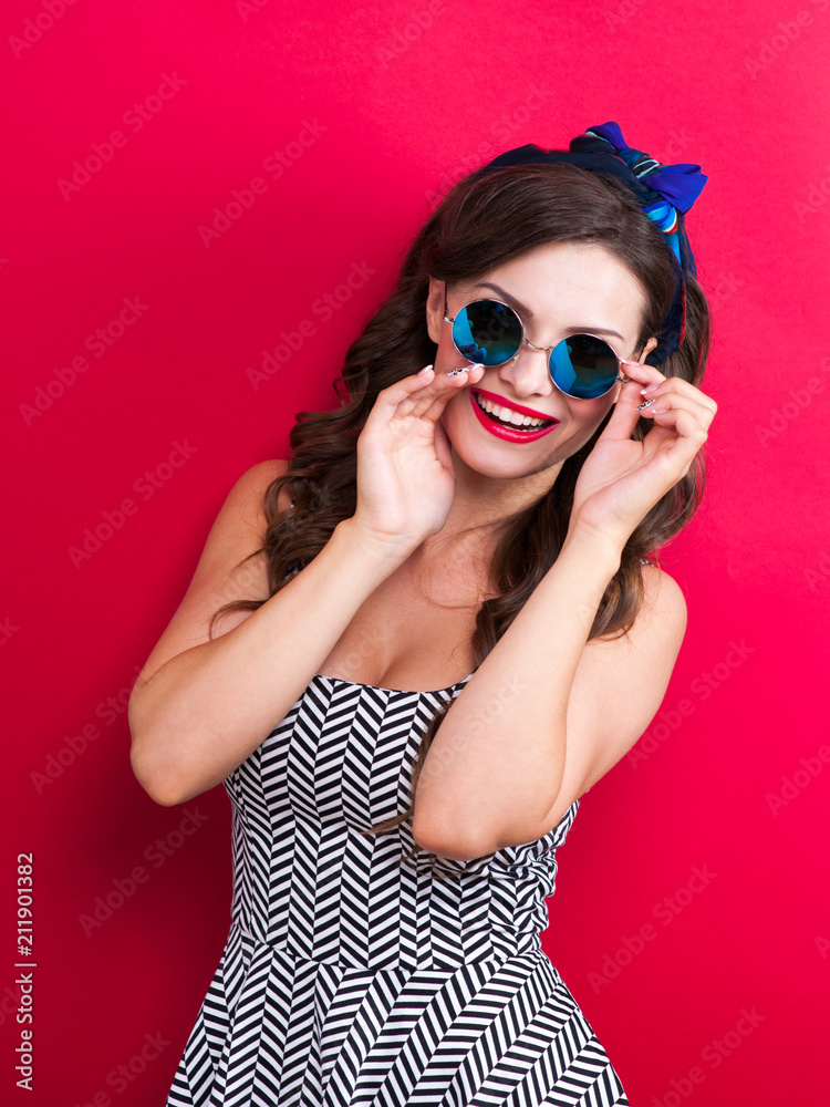 The girl in a red dress on a red background in the studio