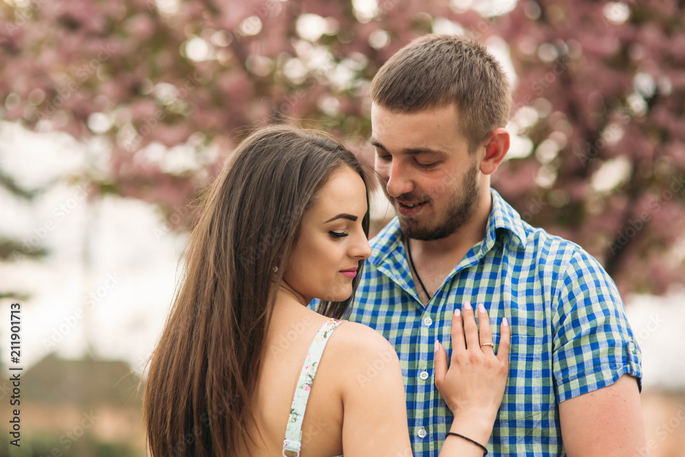 Young couple in love resting in the blooming garden. white blooming trees Young couple in love resting in the blooming garden. white blooming trees