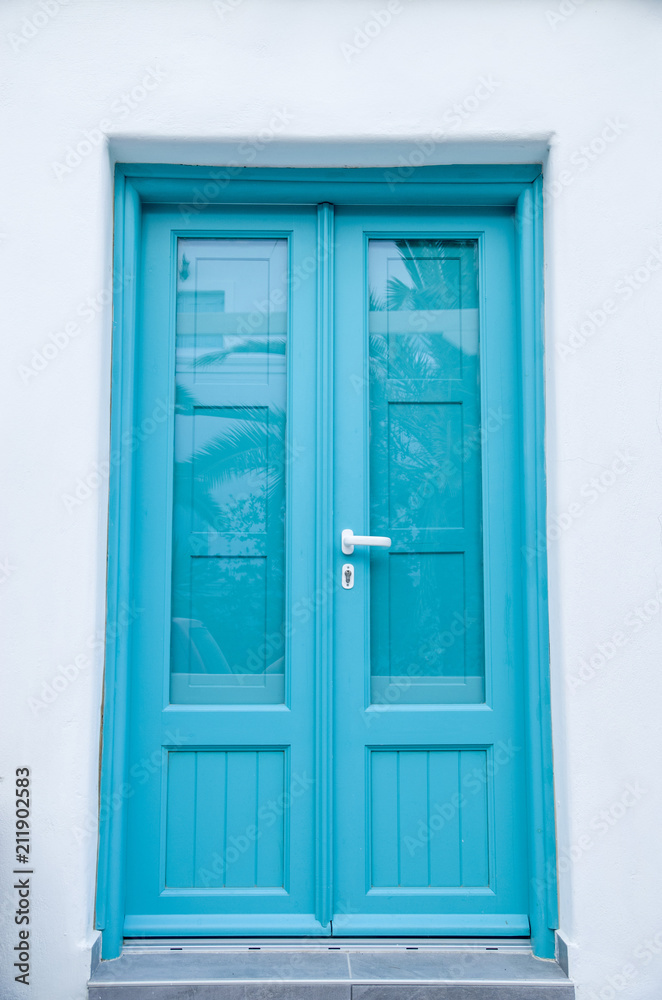 New blue wooden door on white wall, Santorini New blue wooden door on white wall, Santorini