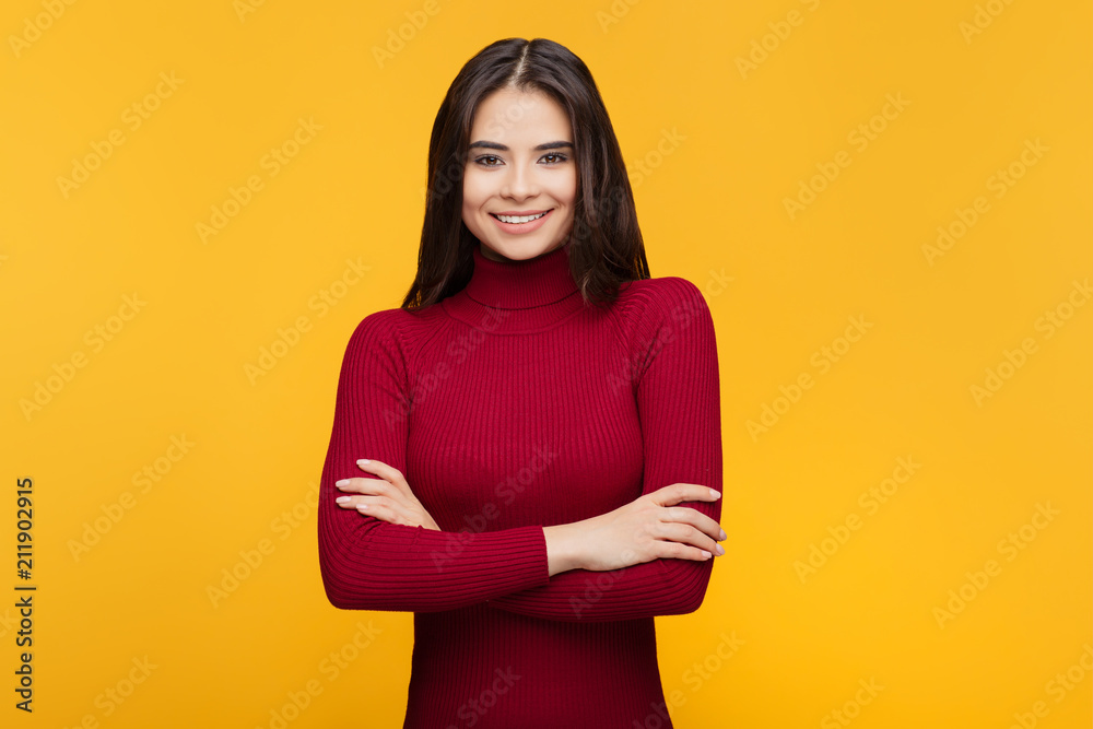 Attractive young woman in red dress is posing on orange background. Attractive young woman in red dress is posing on orange background.