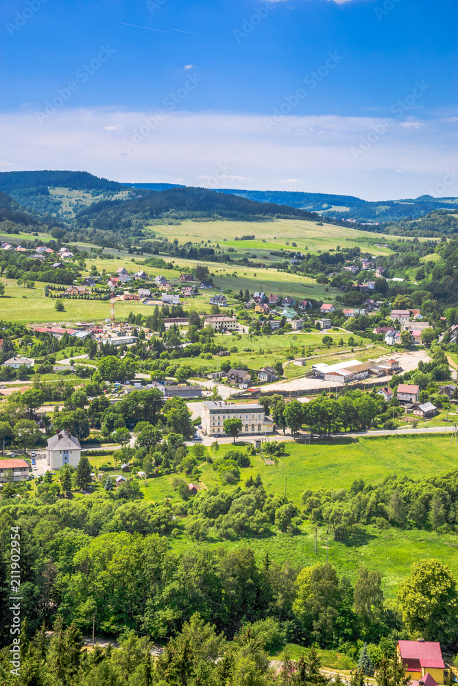 Aerial view of rural scenery in the valley with green town and houses on foothills