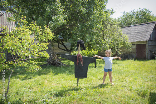 In the summer in the village in the garden near the bugbear is a little girl.