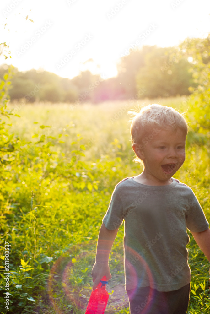 Fototapeta premium Little boy in summer sunny day holding toy in hands and running.