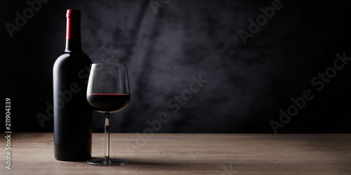 Rotweinflasche mit Weinglas auf Schwarz photo