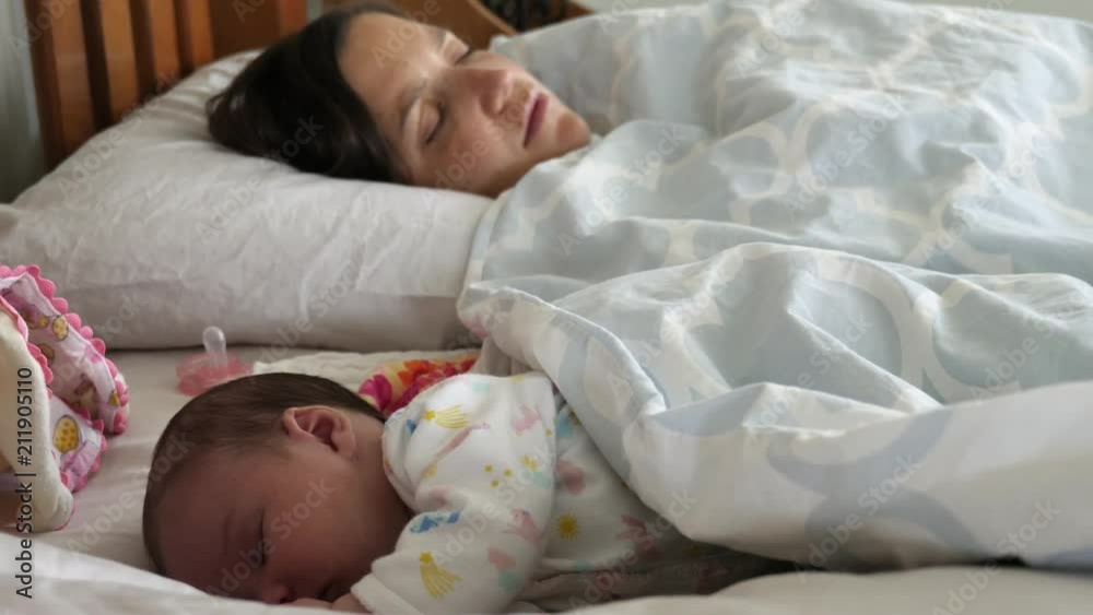 Exhausted mother trying to sleep with her newborn girl in her bed Exhausted mother trying to sleep with her newborn girl in her bed