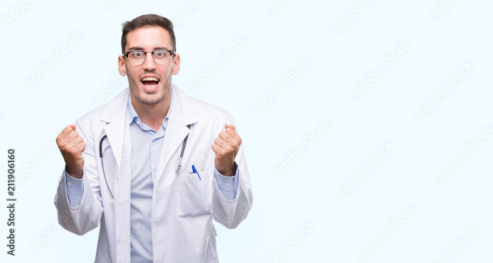 Handsome young doctor man celebrating surprised and amazed for success with arms raised and open eyes. Winner concept. Handsome young doctor man celebrating surprised and amazed for success with arms raised and open eyes. Winner concept.