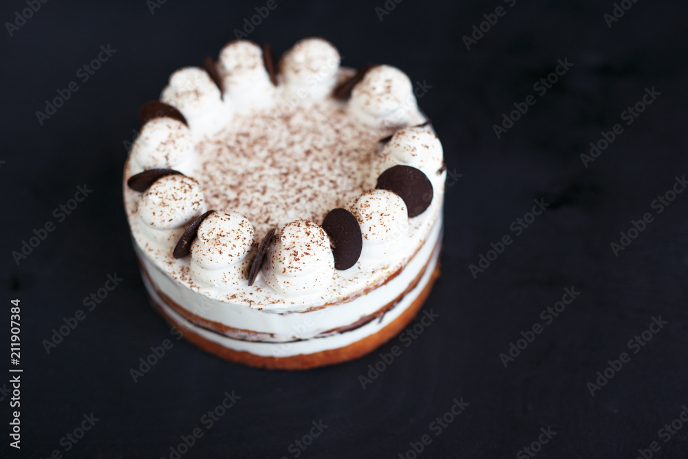 Naklejka premium White sponge cake with chocolate on a black background