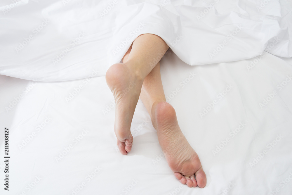 feet of sleeping woman upside down on a white bed. feet of sleeping woman upside down on a white bed.