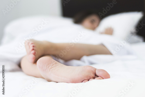 feet of sleeping woman upside down on a white bed with shallow depth of field