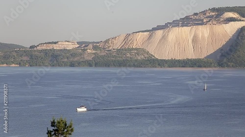 Day panoramic view of a large yacht or fishing boat on the high seas, a lake, a river, a harbor in the background of a mountain. Pan effect. The concept of travel and leisure