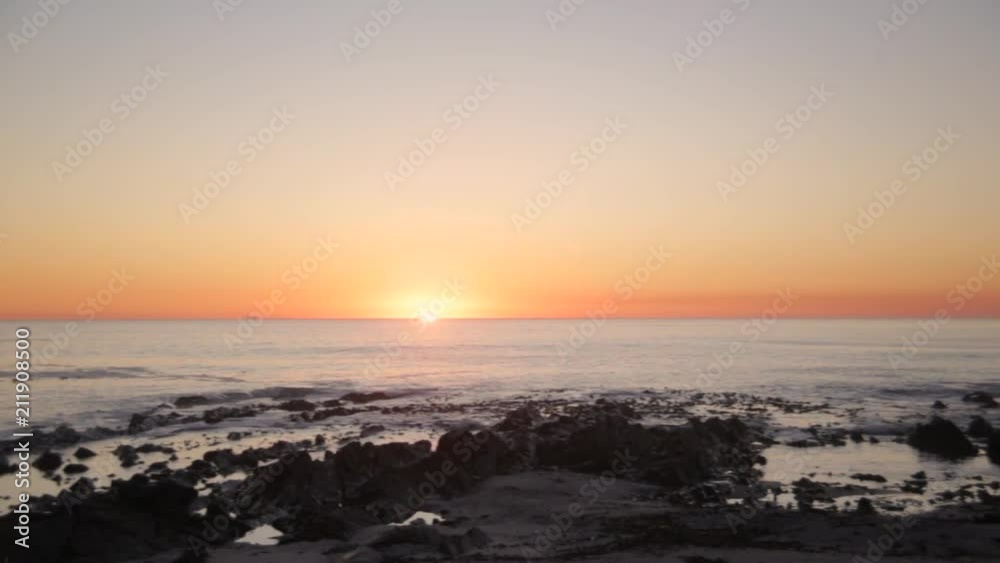 Left to right Pan of a golden hour sunset in cape town with the calm waves of the ocean Left to right Pan of a golden hour sunset in cape town with the calm waves of the ocean