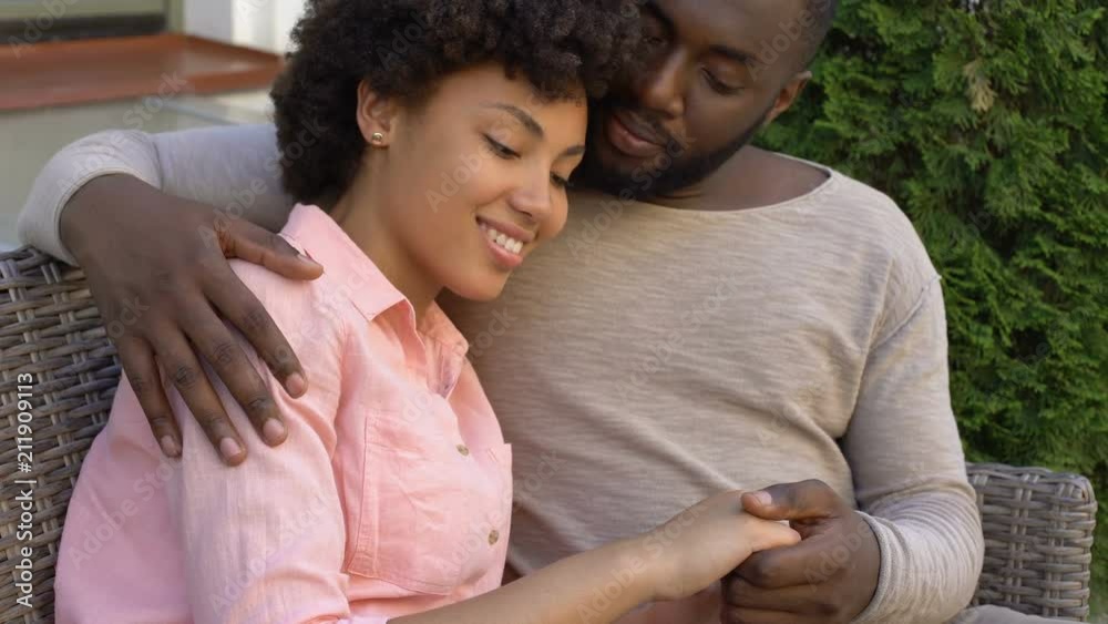 Happy african couple hugging on bench, outdoor date in city cafe, closeness Happy african couple hugging on bench, outdoor date in city cafe, closeness