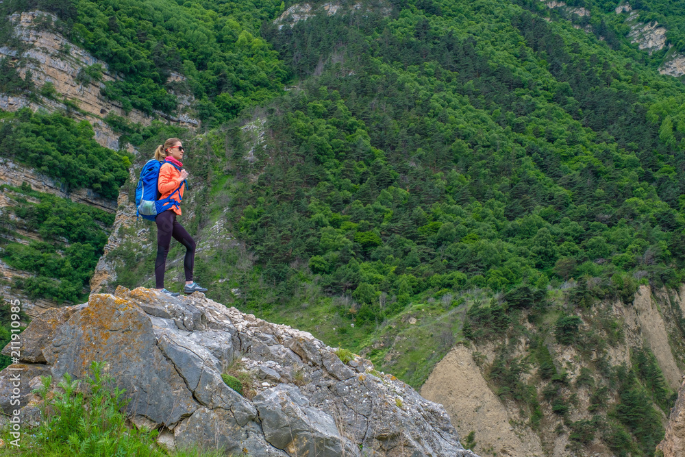 Girl with a backpack in the mountains.