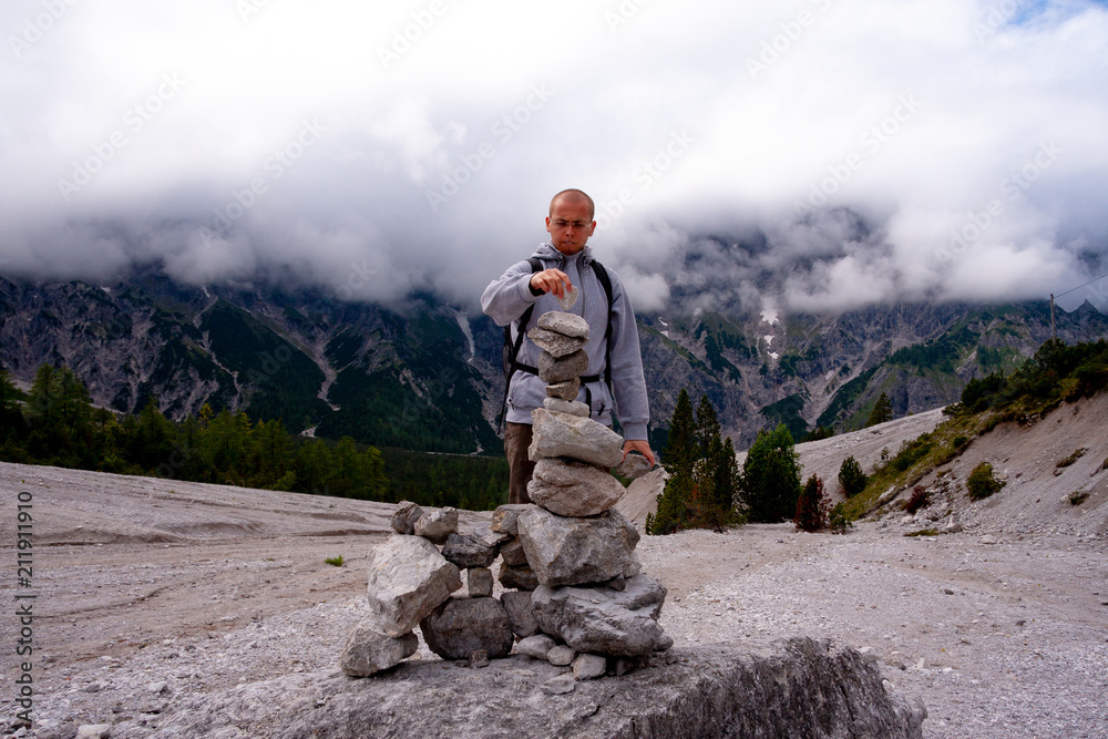 Man is builing a stack made of stones during his hiking trip Man is builing a stack made of stones during his hiking trip