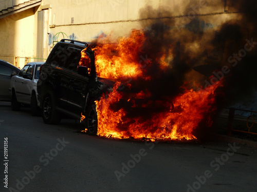 Burning car in the parking lot. Car catching fire, after act of vandalism or road incident © Svetalik
