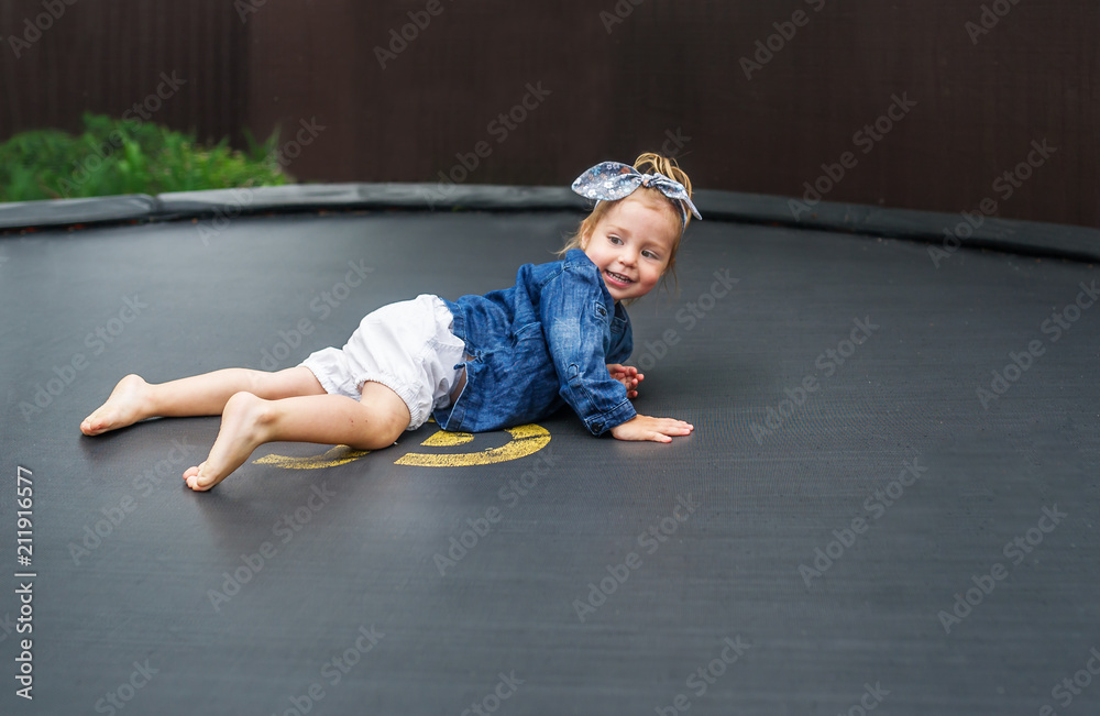 Active barefoot baby girl plays outdoors in playground. Portrait of the  little girl on a trampoline Photos | Adobe Stock