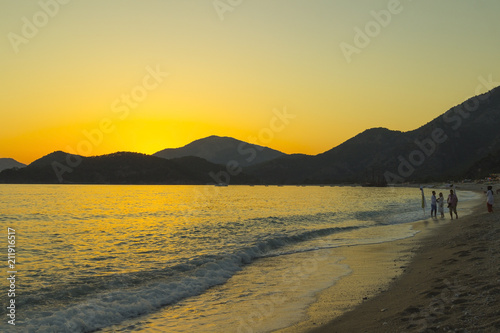 Mediterranean landscape. Sunset on the sea with flowing bright colored rays of the sun through the clouds. Silhouettes of mountains. Background.