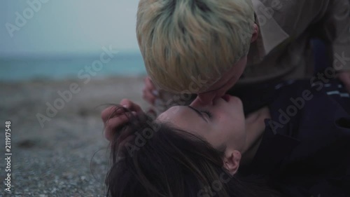 Couple lie on the sand and kissing.