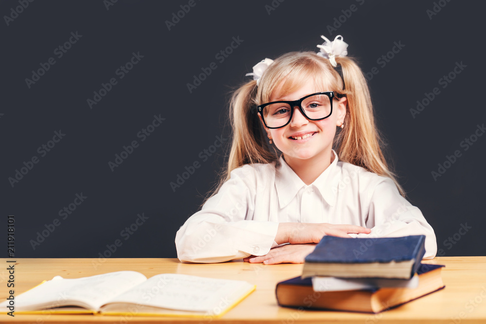 Portrait of cute young girl wears smart eyeglasses learning English language with book before dark background Portrait of cute young girl wears smart eyeglasses learning English language with book before dark background