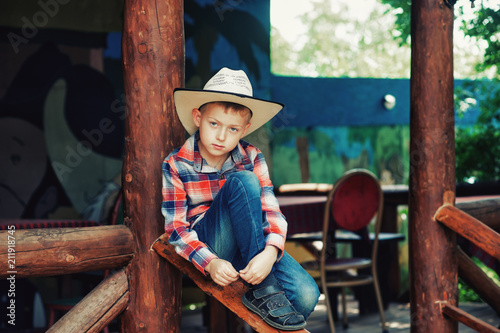 Portrait of a boy in a stylish hat in a stylized street cafe