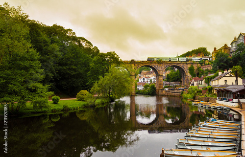 View of the Nidd River and rowing boats from the ruins of Knaresborough Castle with the train passing through the old bridge in a cloudy day. photo