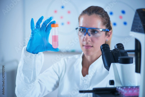 Young female scientist holding liquid sample