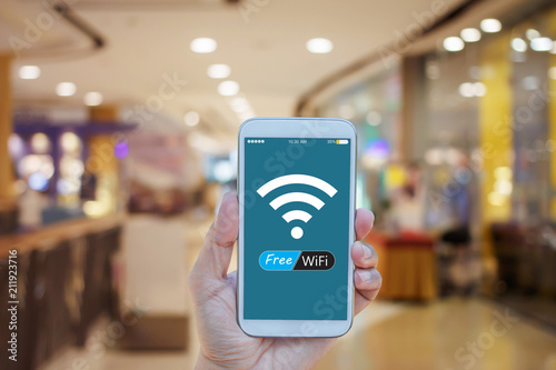 Wallpaper Mural Hand holding smartphone with Free WiFi on screen over blurred in shopping mall background Torontodigital.ca
