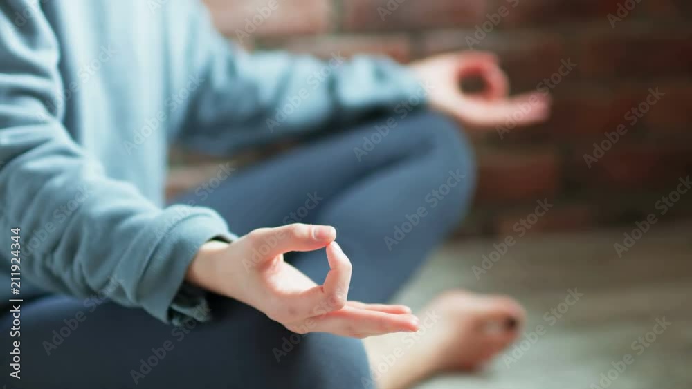 Young woman practicing yoga indoors. Close-up of female hands in lotus pose Young woman practicing yoga indoors. Close-up of female hands in lotus pose