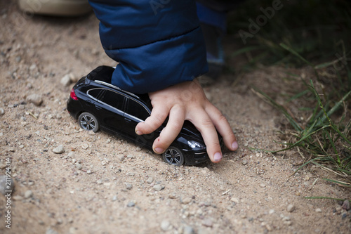 A boy is playing with a toy. Hand of a boy with a black toy car.