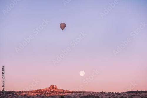 An interesting mountain landscape full moon and flying in the sky a balloon in the early morning. 