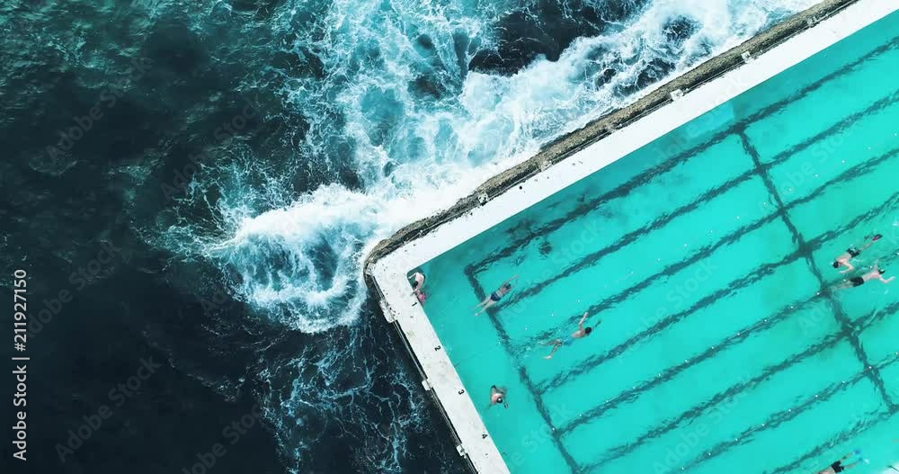 Swimming pool at Bondi Beach, Australia.
Aerial shot looking directly down at a section of the pool with swimmers and waves crashing.