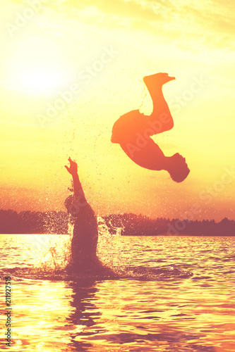Glückliche junge Menschen laufen und springen am See beim Sonnenuntergang © Thaut Images