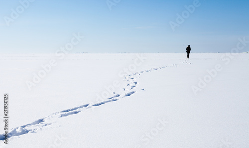 Person walks on frozen sea with snow