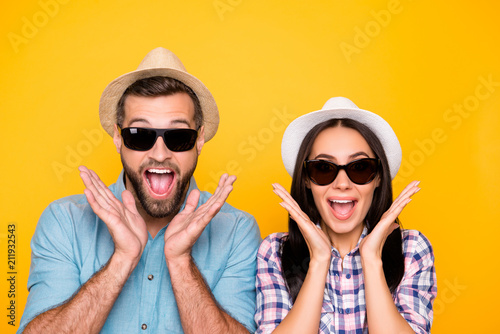Head shot portrait of surprised glad traveler in straw hats black eyeglasses with wide open mouth holding palms near face isolated on vivid yellow background