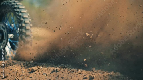 Close up of autobike's wheel starting motion and raising clouds of dust photo