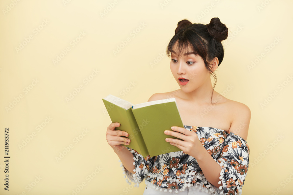 Young Asian woman reading a book with surprised face Young Asian woman reading a book with surprised face