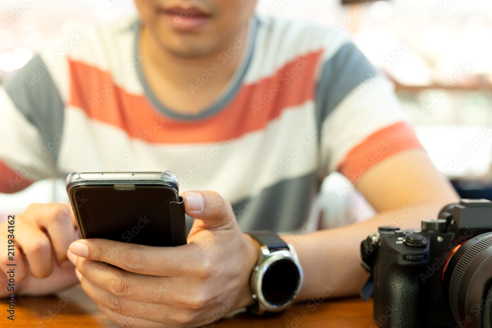 Man's hands using smart phone with DSLR camera on table