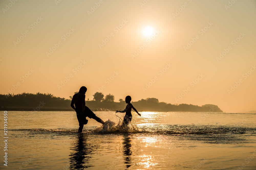 Silhouette of children playing water with friend