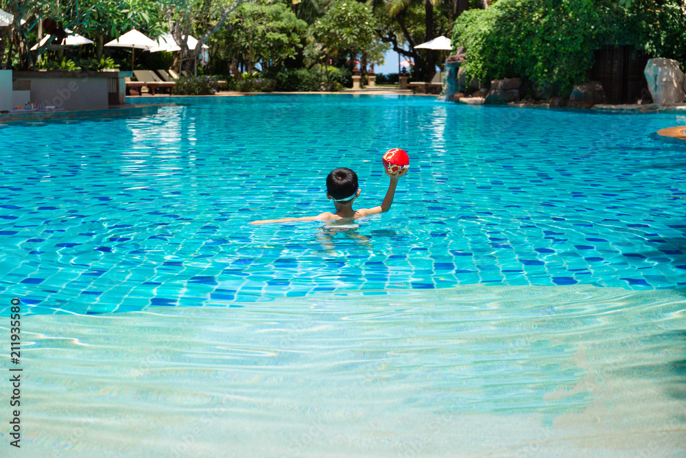 Little boy playing a ball game in swimming pool