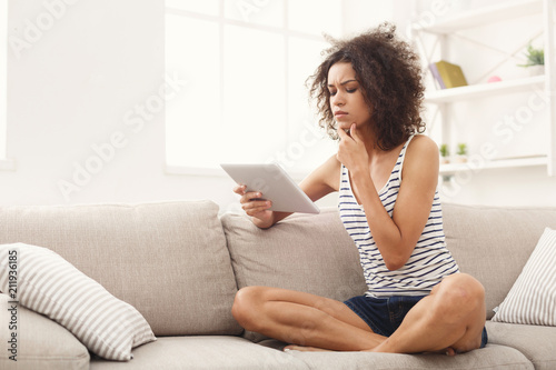 Young pensive girl with digital tablet at home
